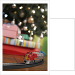 Toy train running beneath Christmas tree by Anonymous