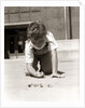 1950s Boy Ready To Shoot Kneeling On School Yard Ground Playing Game Of Marbles by Anonymous