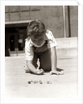 1950s Boy Ready To Shoot Kneeling On School Yard Ground Playing Game Of Marbles by Anonymous