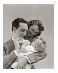 1940s Father Cradling Baby Daughter Feeding Her Bottle With Mother Looking Over His Shoulder by Anonymous