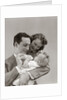 1940s Father Cradling Baby Daughter Feeding Her Bottle With Mother Looking Over His Shoulder by Anonymous