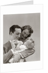 1940s Father Cradling Baby Daughter Feeding Her Bottle With Mother Looking Over His Shoulder by Anonymous