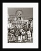 1960s Baby Sitting In Supermarket Cart Full Of Cans Eating Candy Bar With A Messy Face by Anonymous