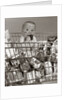 1960s Baby Sitting In Supermarket Cart Full Of Cans Eating Candy Bar With A Messy Face by Anonymous