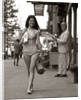 1970s Man Ogling Sexy Young Woman Walking Down City Street Wearing Only A Bikini by Anonymous
