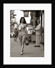 1970s Man Ogling Sexy Young Woman Walking Down City Street Wearing Only A Bikini by Anonymous