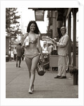 1970s Man Ogling Sexy Young Woman Walking Down City Street Wearing Only A Bikini by Anonymous