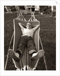 1950s Relaxed Boy Lying In Suburban Backyard Hammock by Anonymous
