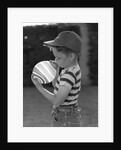 1950s Side View Of Boy In Baseball Cap and Striped T-Shirt Blowing Up Swirled Balloon by Anonymous