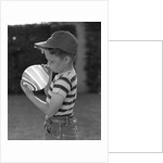 1950s Side View Of Boy In Baseball Cap and Striped T-Shirt Blowing Up Swirled Balloon by Anonymous