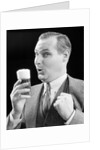 1930s Man Holding Full Foamy Glass Of Beer Making A Funny Face With His Thumb Hooked Confidently Under His Vest by Anonymous