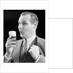 1930s Man Holding Full Foamy Glass Of Beer Making A Funny Face With His Thumb Hooked Confidently Under His Vest by Anonymous