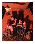 1960s 1970s Grandfather Telling Scary Story To Boys By Tent At Night Campsite In Shadows by Anonymous