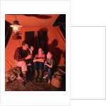 1960s 1970s Grandfather Telling Scary Story To Boys By Tent At Night Campsite In Shadows by Anonymous