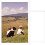 1960s Back Of Two Boys With Black And White Dog Sitting Hillside Field Looking Down To Farm by Anonymous