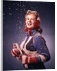 1960s Young Woman Wearing Red Mittens Ear Muffs Blue Sweater Holding Ice Skates In Falling Snow by Anonymous