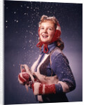 1960s Young Woman Wearing Red Mittens Ear Muffs Blue Sweater Holding Ice Skates In Falling Snow by Anonymous