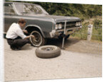 1960s Man Changing Flat Tire On Car At Side Of Rural Road Car Jack Tools Tire Iron by Anonymous