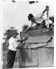 1930s Pair Of Boys Building Shack One Nailing Board To Side One On Roof With Saw by Anonymous