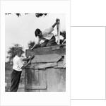 1930s Pair Of Boys Building Shack One Nailing Board To Side One On Roof With Saw by Anonymous