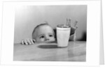 1950s Toddler Reaching Up To Table To Grab Milk Glass by Anonymous