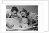1950s Parents Leaning Over Tub Bathing Happy Baby by Anonymous