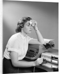 1950s Ailing Secretary Sitting At Desk With Typewriter And Dictation Machine Holding Handkerchief To Forehead by Anonymous