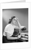 1950s Ailing Secretary Sitting At Desk With Typewriter And Dictation Machine Holding Handkerchief To Forehead by Anonymous