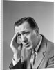 1960s Portrait Man In Suit and Tie With Wrinkled Brow Wincing and Holding Forehead by Anonymous