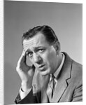1960s Portrait Man In Suit and Tie With Wrinkled Brow Wincing and Holding Forehead by Anonymous