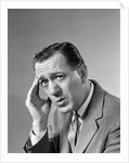 1960s Portrait Man In Suit and Tie With Wrinkled Brow Wincing and Holding Forehead by Anonymous