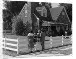 1950s Family Standing By White Fence Looking At Brick House by Anonymous