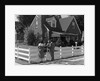1950s Family Standing By White Fence Looking At Brick House by Anonymous