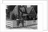 1950s Family Standing By White Fence Looking At Brick House by Anonymous