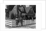 1950s Family Standing By White Fence Looking At Brick House by Anonymous