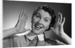 1950s Happy Woman Holding Hands Up Beside Her Head by Anonymous