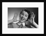 1950s Happy Woman Holding Hands Up Beside Her Head by Anonymous