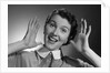 1950s Happy Woman Holding Hands Up Beside Her Head by Anonymous