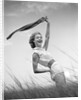 1950s 1960s Young Woman Bending Back Holding Scarf In The Wind Standing On Grassy Beach Dune by Anonymous