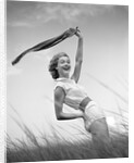 1950s 1960s Young Woman Bending Back Holding Scarf In The Wind Standing On Grassy Beach Dune by Anonymous