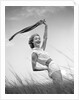 1950s 1960s Young Woman Bending Back Holding Scarf In The Wind Standing On Grassy Beach Dune by Anonymous