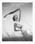 1950s 1960s Young Woman Bending Back Holding Scarf In The Wind Standing On Grassy Beach Dune by Anonymous
