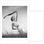 1950s 1960s Young Woman Bending Back Holding Scarf In The Wind Standing On Grassy Beach Dune by Anonymous