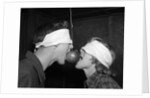 1950s Blindfolded Couple Trying To Eat An Apple Hanging In Air From A String Inside by Anonymous