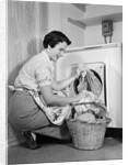 1950s Woman Kneeling Removing Clothes Laundry From Automatic Dryer by Anonymous