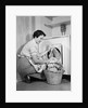 1950s Woman Kneeling Removing Clothes Laundry From Automatic Dryer by Anonymous