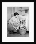 1950s Woman Kneeling Removing Clothes Laundry From Automatic Dryer by Anonymous