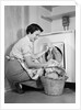 1950s Woman Kneeling Removing Clothes Laundry From Automatic Dryer by Anonymous