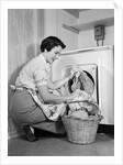 1950s Woman Kneeling Removing Clothes Laundry From Automatic Dryer by Anonymous