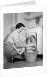 1950s Woman Kneeling Removing Clothes Laundry From Automatic Dryer by Anonymous